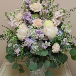 Pastel bouquet of white roses, hydrangeas, and lavender blooms in a metal vase