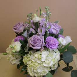 Lavender roses and white hydrangeas in a purple vase