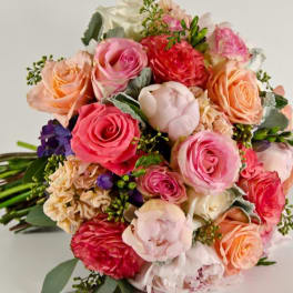 Bouquet of pink, peach, and red roses with mixed blooms