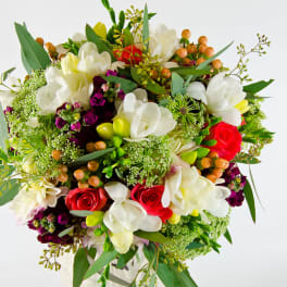 Bouquet of white orchids and red roses with mixed greenery