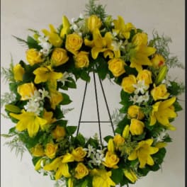 Yellow floral wreath with roses and lilies on a stand