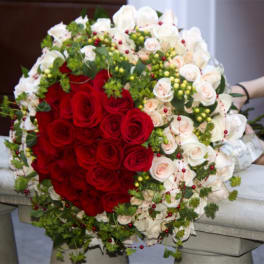Large bouquet of red and white roses with greenery and berry accents