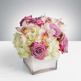 Pink roses and pale orchids in a square glass vase