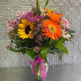Mixed bouquet with sunflowers, gerbera daisies, and pink lilies in a glass vase