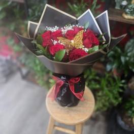 Bouquet of red roses with a butterfly decoration in black wrap