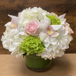 White hydrangeas with pink roses and green blooms in a glass vase