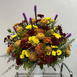 Large mixed bouquet in a white vase with yellow, red, orange, and purple flowers