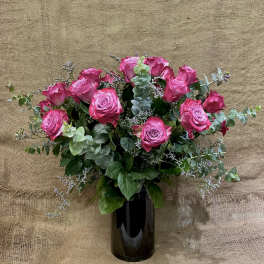 Pink roses arranged in a black vase with eucalyptus