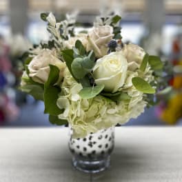 White roses and hydrangeas in a spotted glass vase