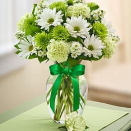 White and green bouquet in a glass vase with a green ribbon