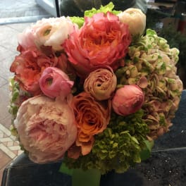 Bouquet of pink, coral, and cream flowers in a green vase