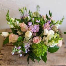 Pastel arrangement of roses, tulips, hydrangea and mixed blooms in a low glass vase