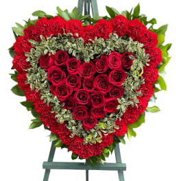Heart-shaped red rose and carnation wreath on an easel