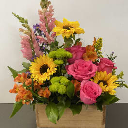 Mixed bouquet with pink roses, sunflowers, and orange alstroemeria in a wooden box