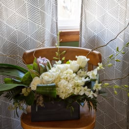 White floral arrangement in a dark rectangular container with long branches