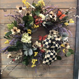 Floral wreath with cream flowers, purple accents, and a checkered bow