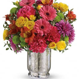 Colorful mixed bouquet in a silver vase with pink, yellow, orange, and purple flowers
