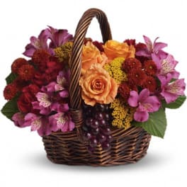 Basket of orange roses and pink flowers with grapes