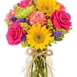 Bouquet of pink roses and yellow daisies in a glass vase with a ribbon