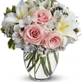 Pink roses and white lilies in a clear glass vase