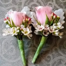 Two small pink rose boutonnieres with white filler flowers