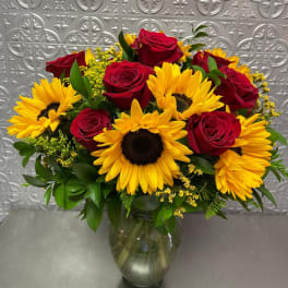 Bouquet of red roses and yellow sunflowers in a glass vase