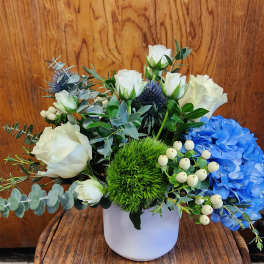 White roses and blue hydrangea in a white vase