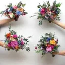Four small mixed flower bouquets held in hands against a white background