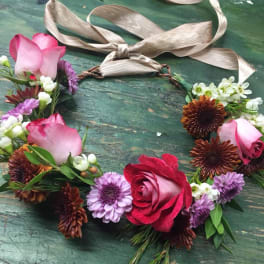 Floral wreath with pink roses and purple daisies on a ribbon tie