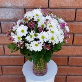 White daisy bouquet with pink filler flowers in a glass vase