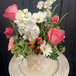 Pink roses and white flowers arranged in a patterned vase