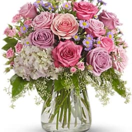 Pink and lavender roses arranged in a clear glass vase