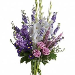 Purple and white floral arrangement in a clear glass vase