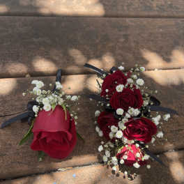 Red rose boutonnieres with baby's breath and black ribbon