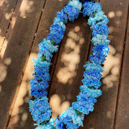 Blue and light blue flower lei on a wooden surface