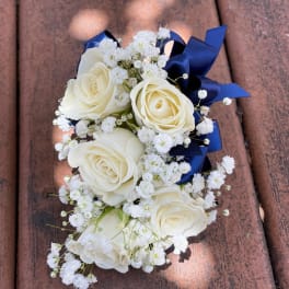 White rose corsage with baby's breath and navy ribbon