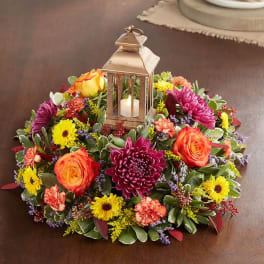 Round floral centerpiece with a lantern candle in the middle