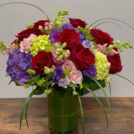 Red roses and purple hydrangeas in a green vase