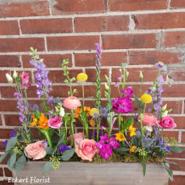 Mixed bouquet in a wooden planter box with pink, purple, and yellow flowers