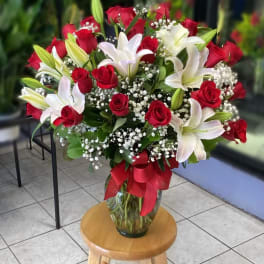 Red roses and white lilies in a glass vase with a red ribbon