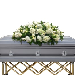 White floral casket spray on a silver casket