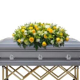 Yellow and white floral casket spray on a gray casket