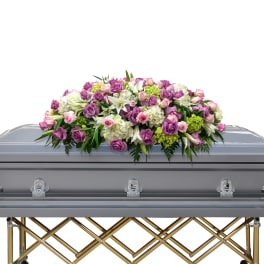 Pink and white floral casket spray on a silver casket