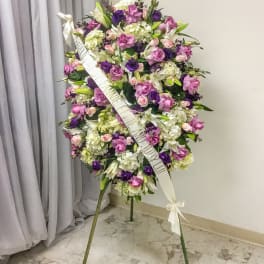 Large standing floral spray in purple, pink, and white with a ribbon