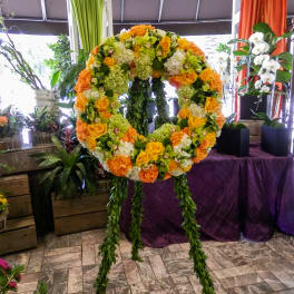 Large floral wreath on a stand with orange, yellow, and white blooms