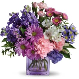 Mixed purple, pink, and white flowers in a purple glass vase