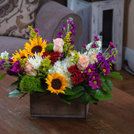 Mixed bouquet with sunflowers, roses, and purple blooms in a wooden box
