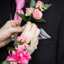 Pink rose boutonniere and corsage on a black suit and wrist
