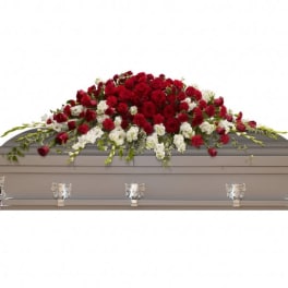 Red and white floral casket spray on a gray coffin
