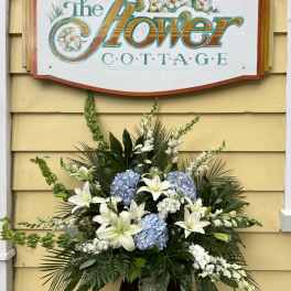 Large floral arrangement with white lilies and blue hydrangeas in a vase